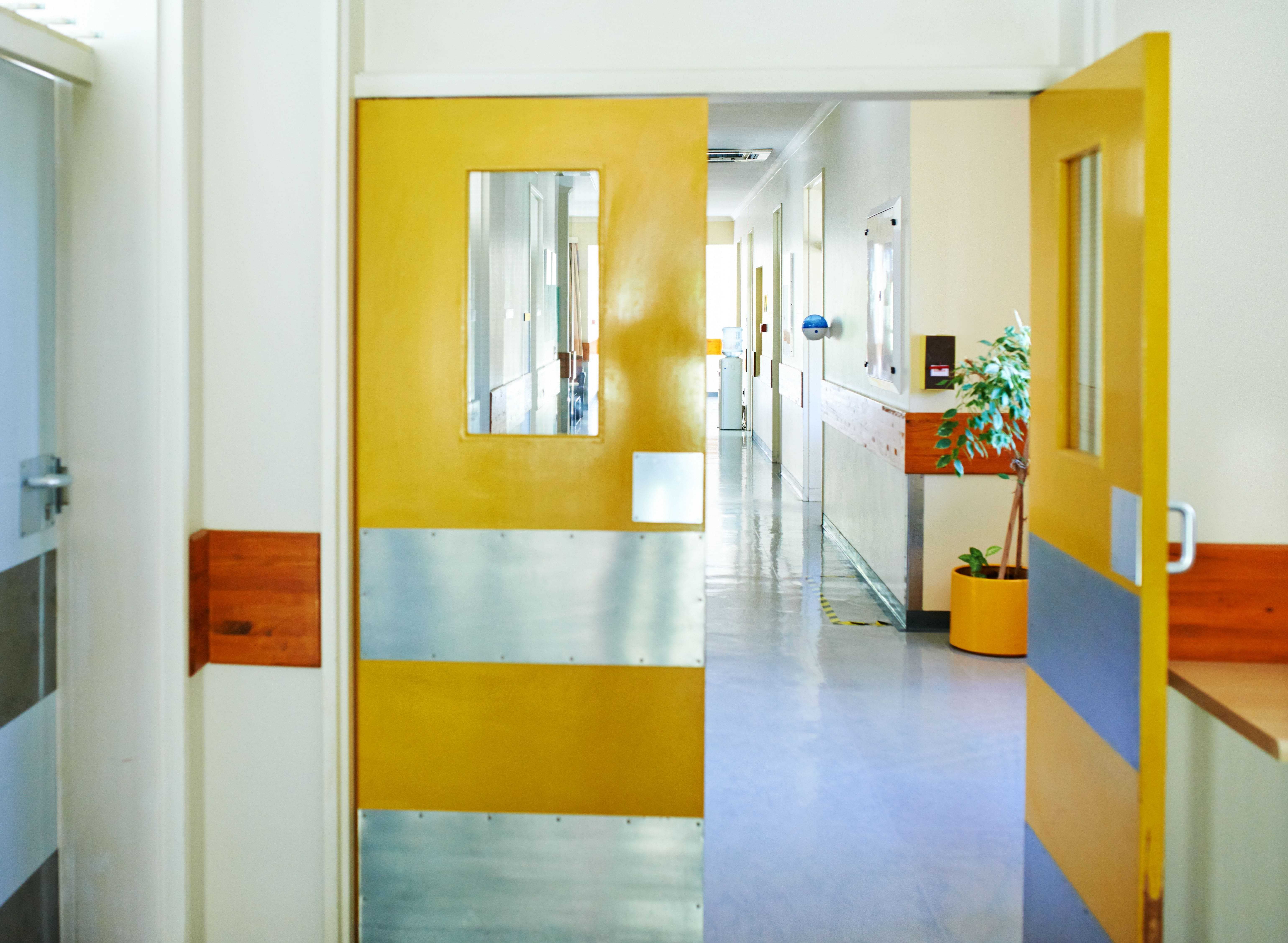 yellow pedestrian swing doors in a healthcare facility corridor
