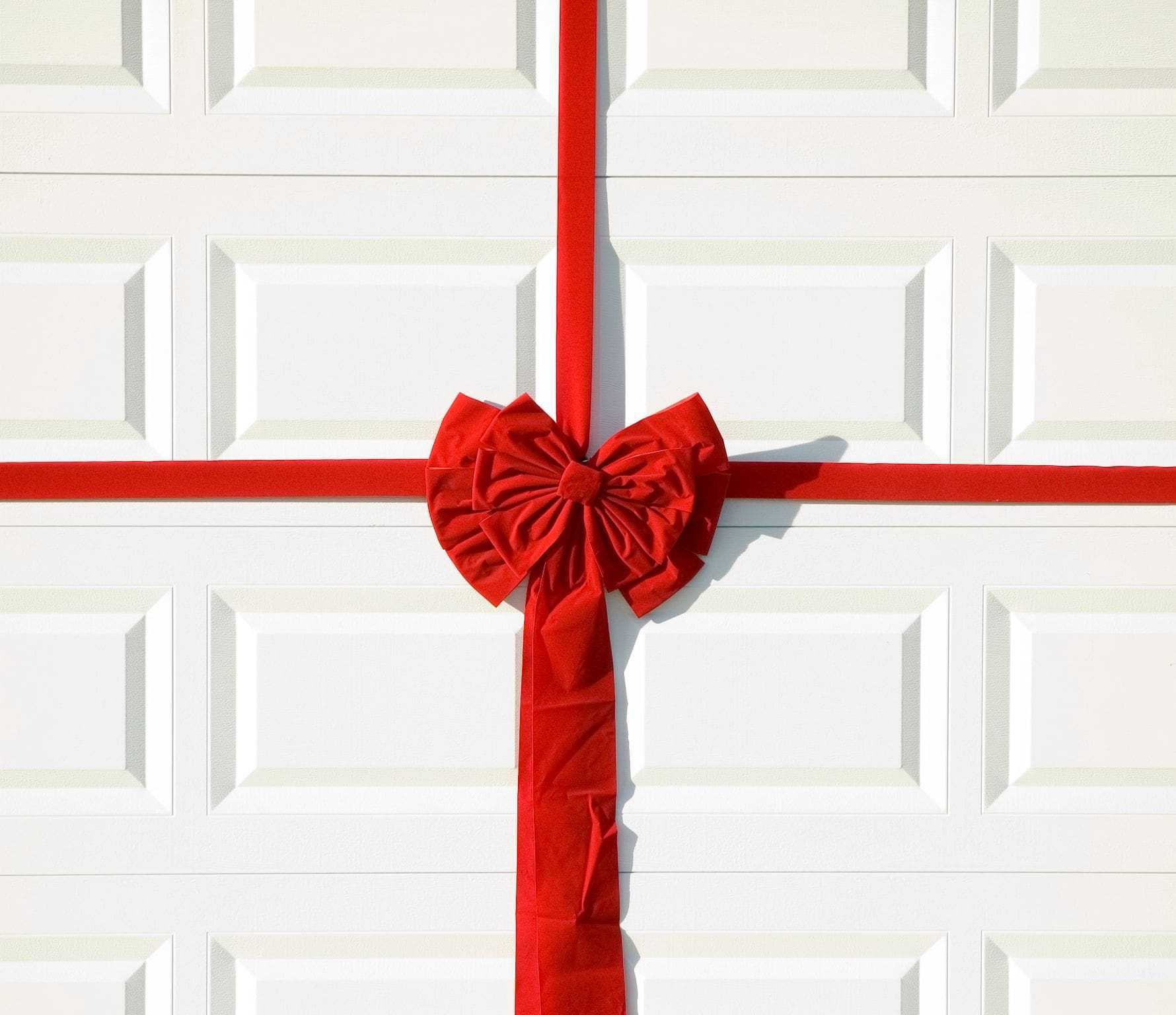a big red bow tied around a white garage door a big red bow tied around a white garage door