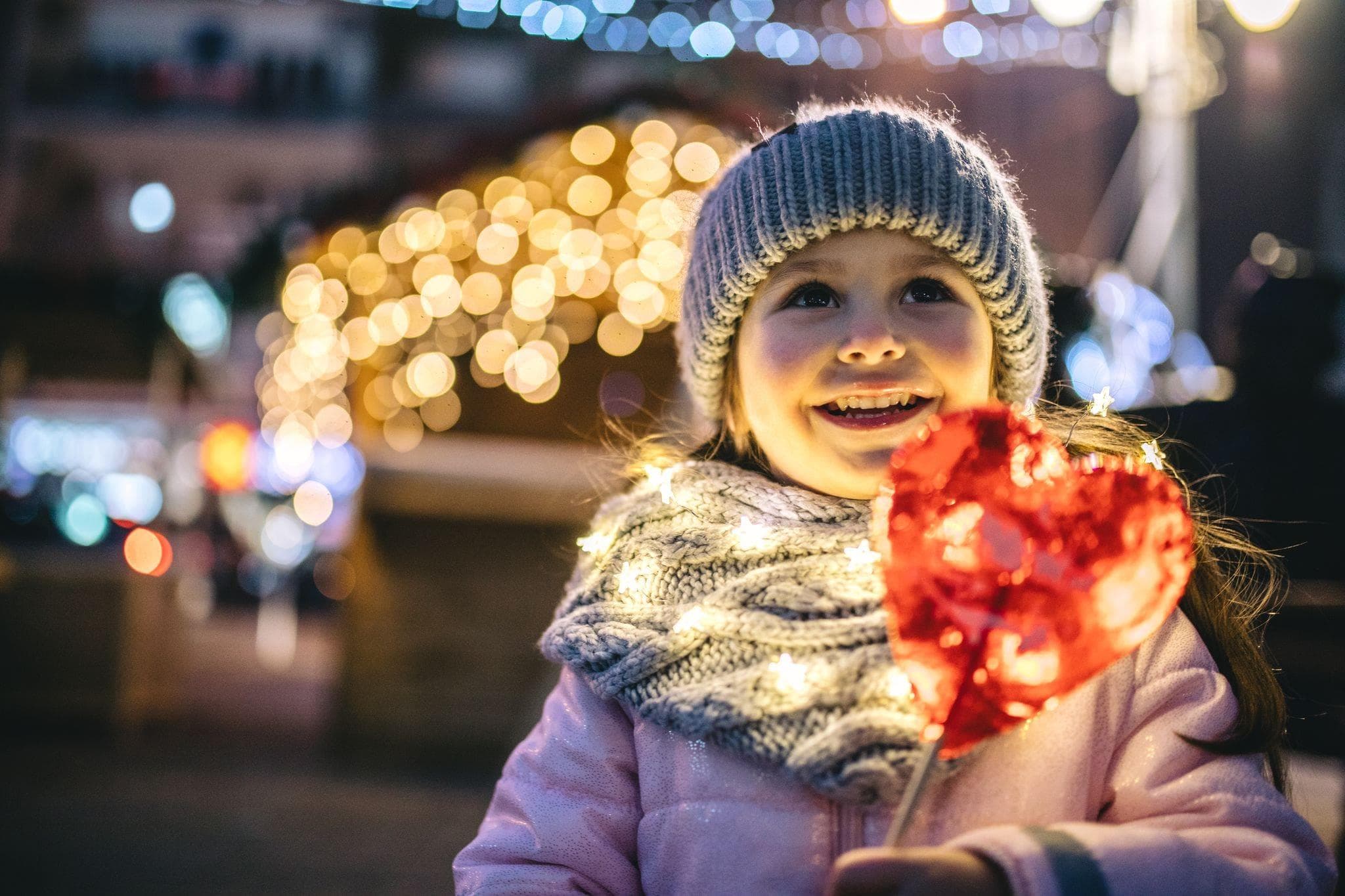 little girl smiling in front of a garage and twinkle lights 