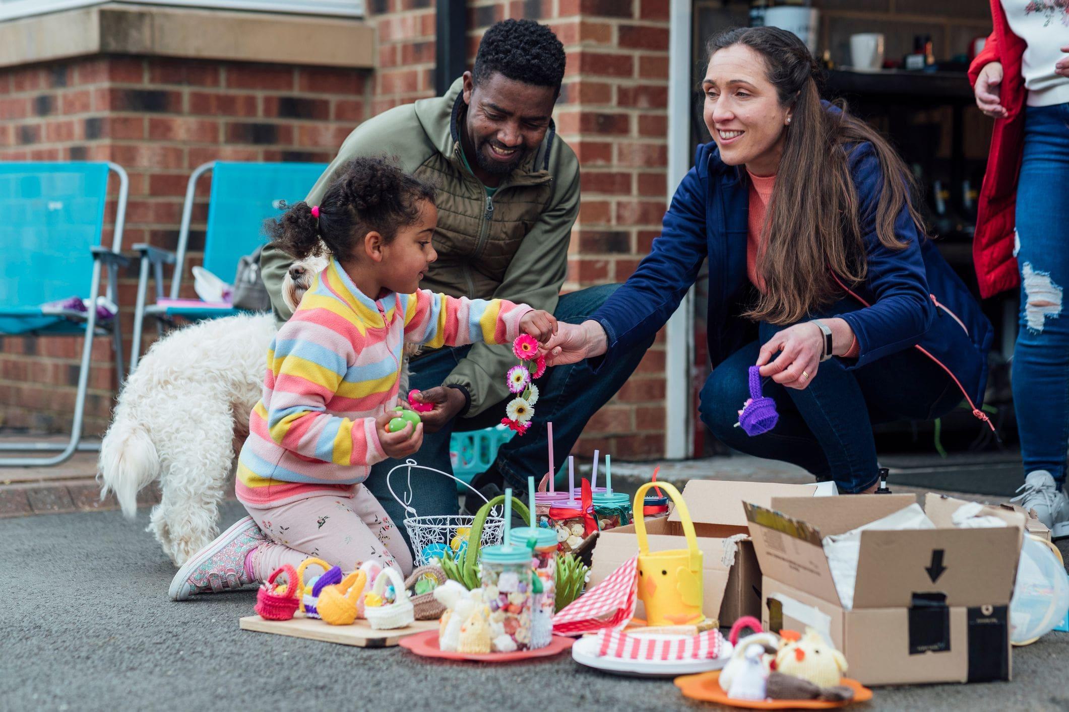 child and parents organizing items for sale beside garage in driveway child and parents organizing items for sale beside garage in driveway