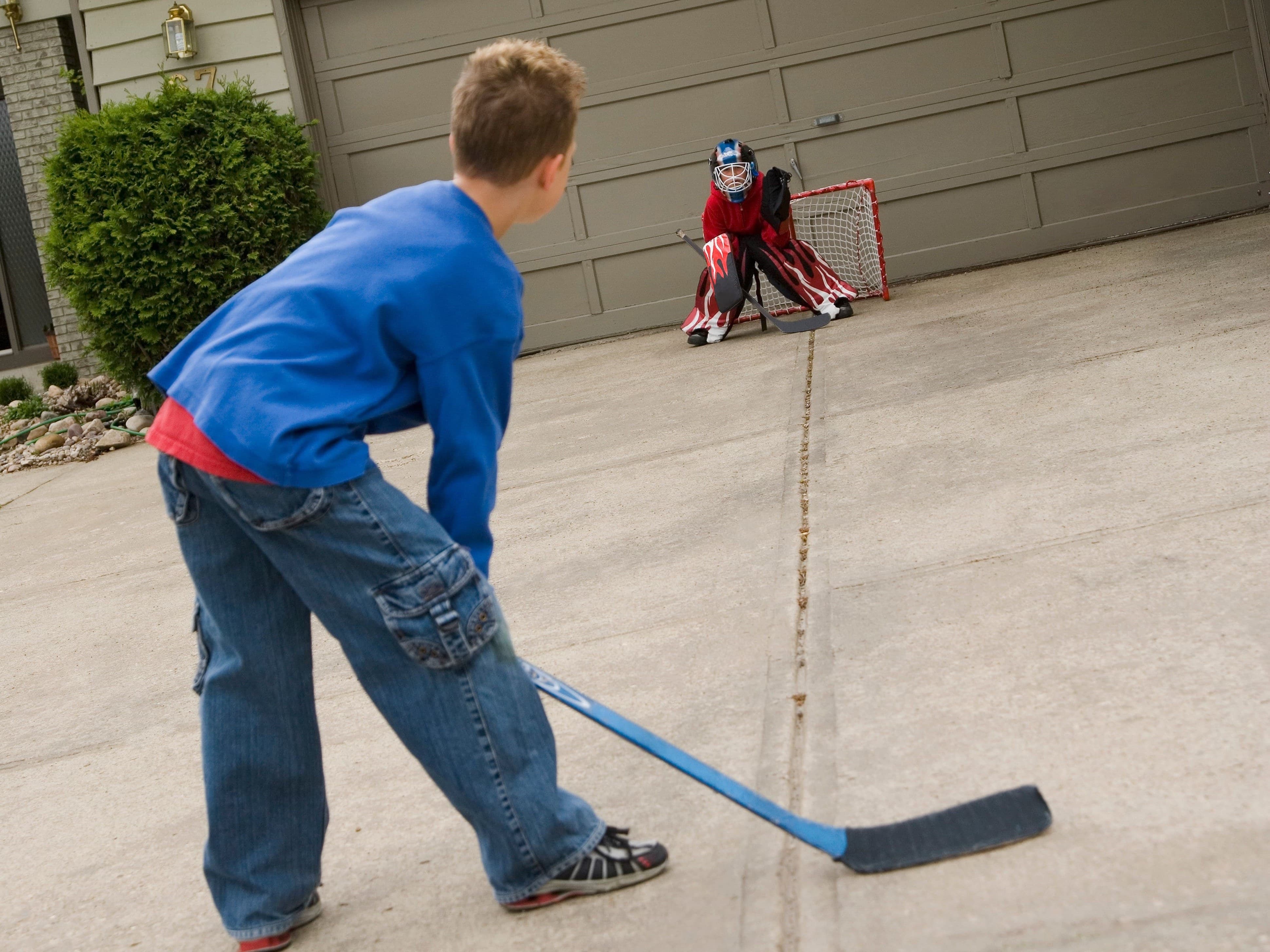 kids playing hockey in driveway with net up against garage door