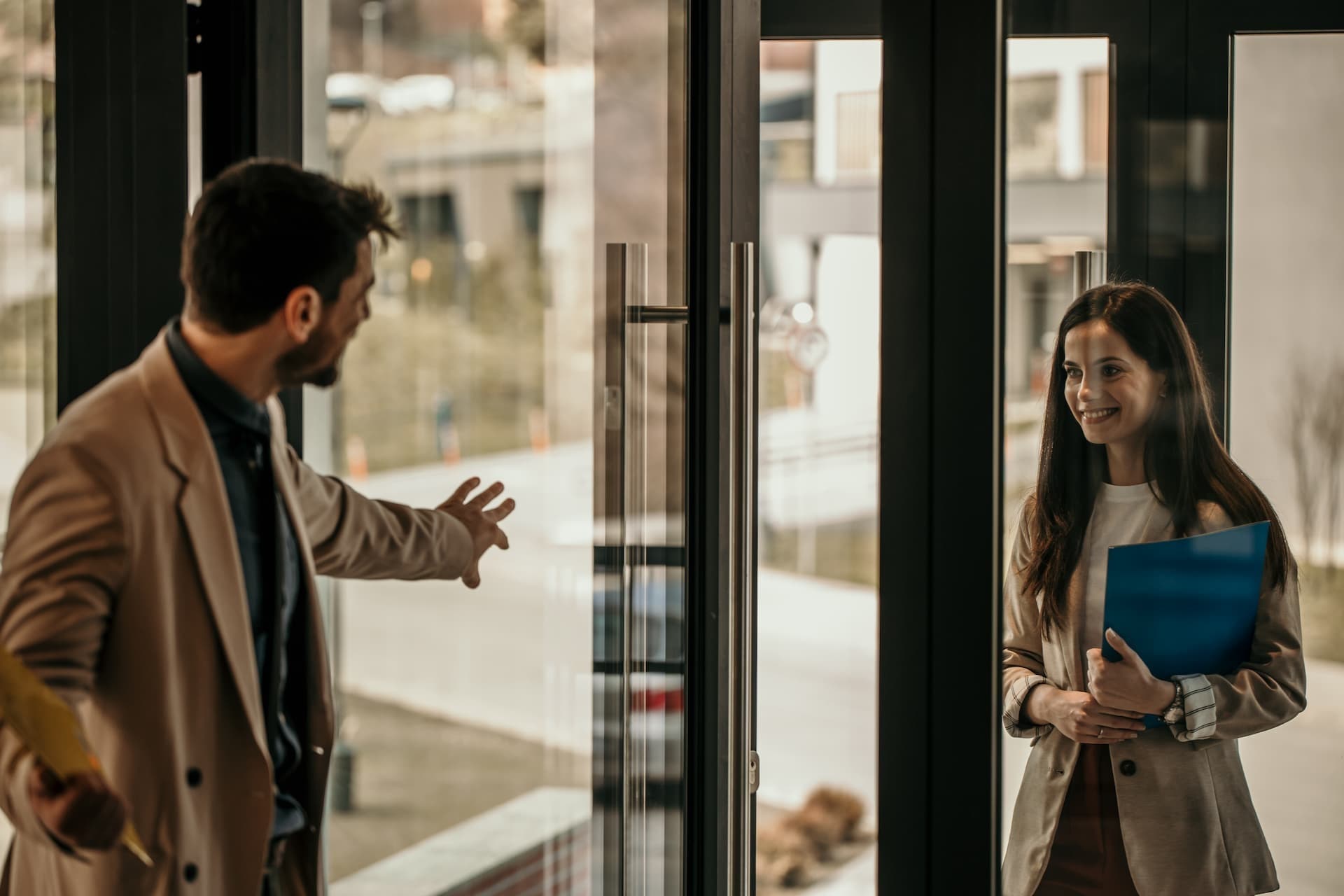 manager welcoming office worker into building at entry door