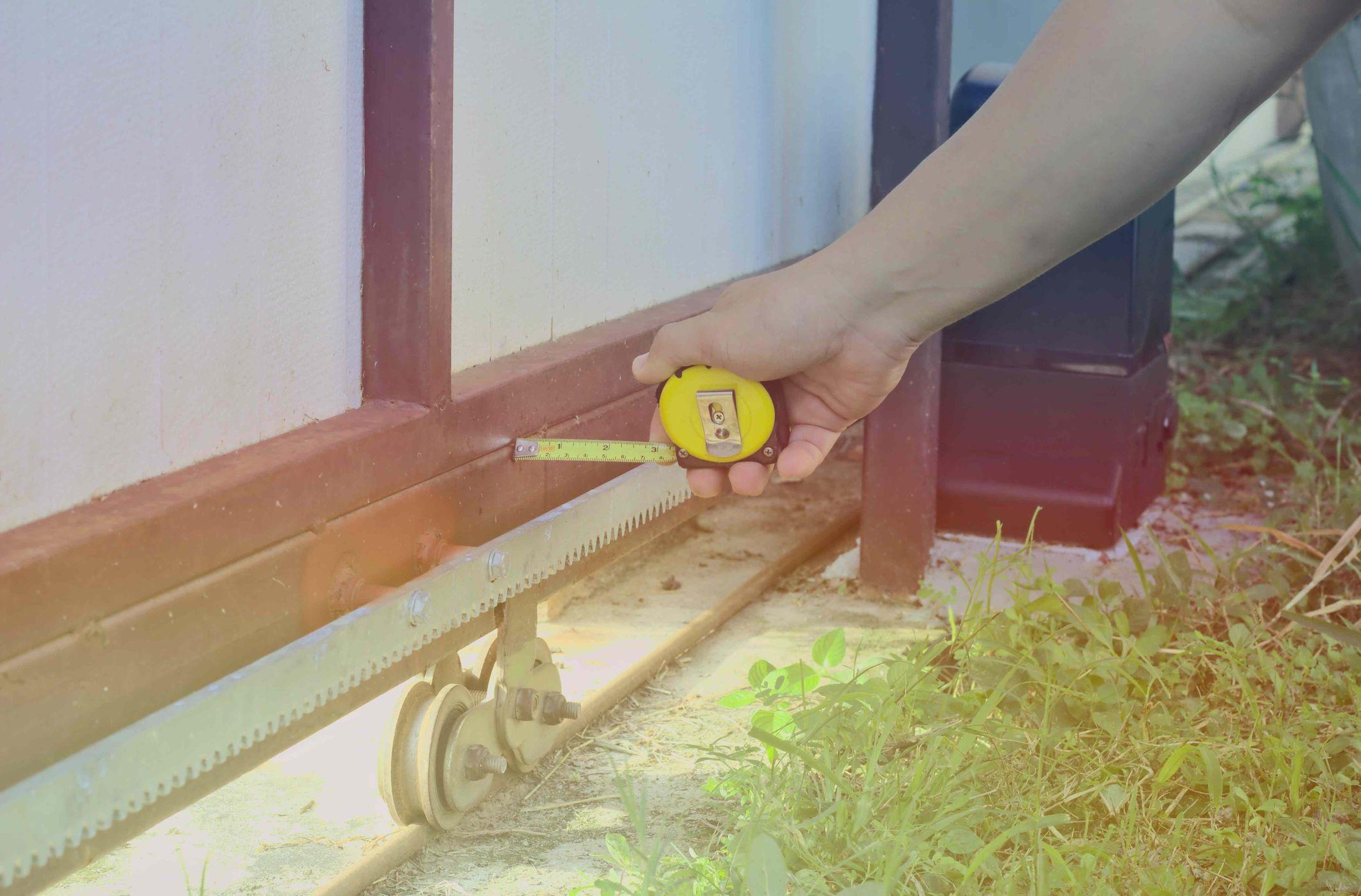 inspecting and measuring an automatic gate with yellow tape inspecting and measuring an automatic gate with yellow tape