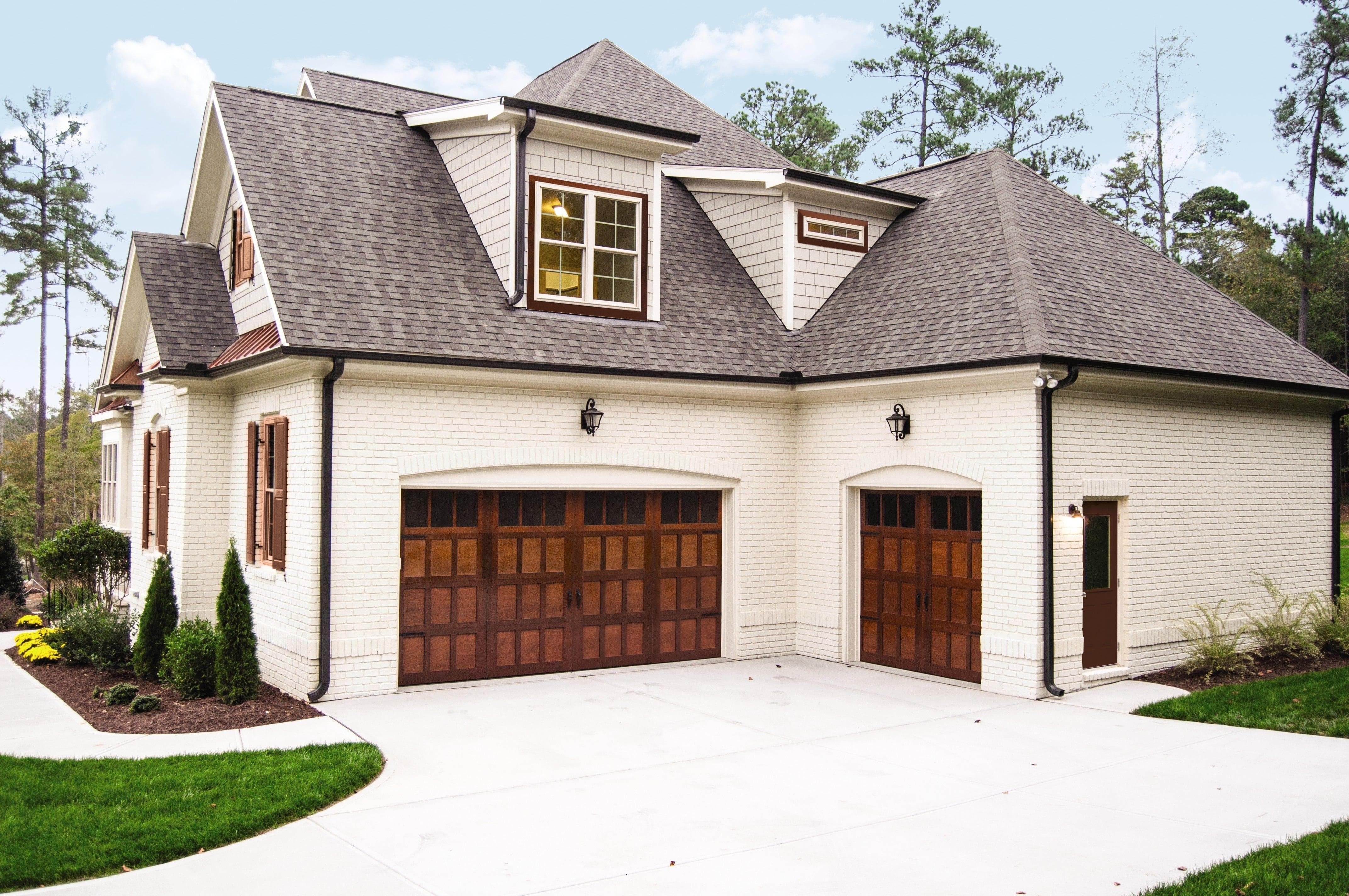 a white brick house with new warm wood wayne dalton garage doors