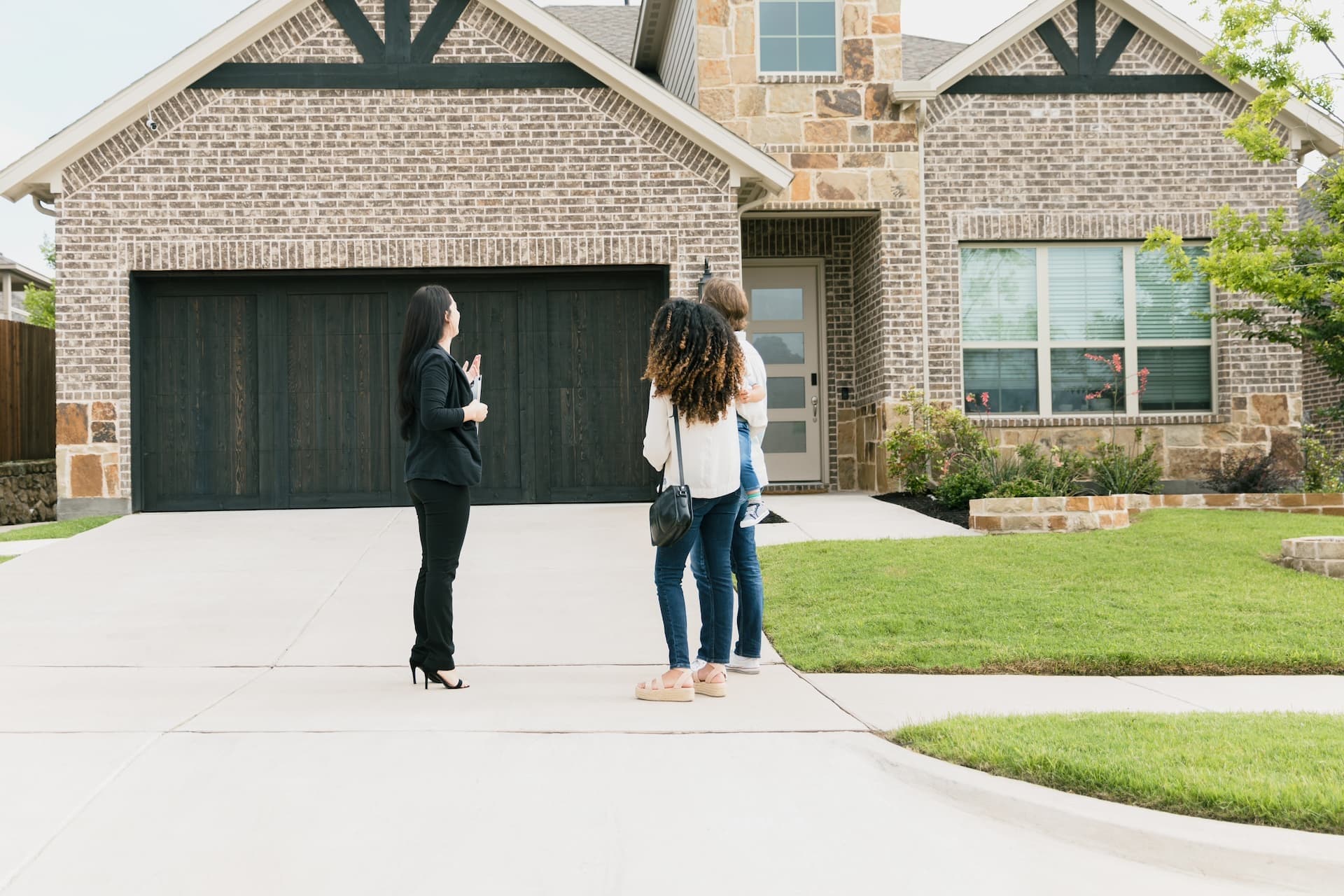 real estate agent showing home exterior to young couple
