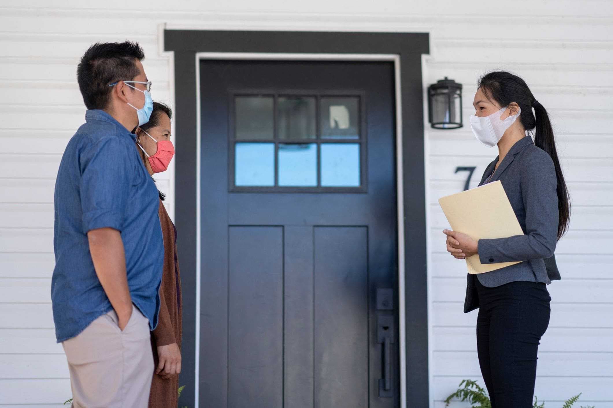 couple meeting with real estate agent in front of new house