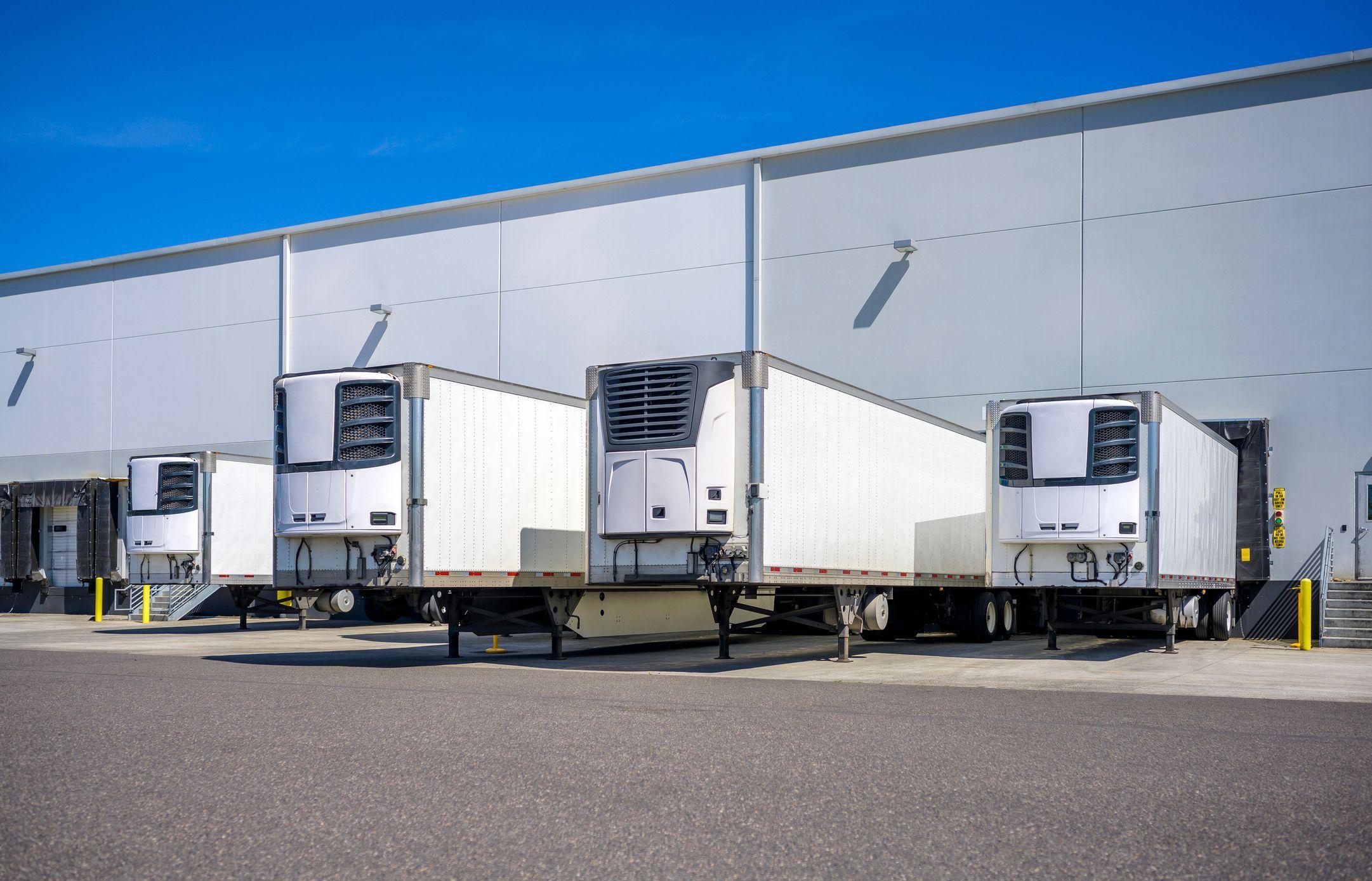 refrigerated trucks lined up at loading dock of warehouse refrigerated trucks lined up at loading dock of warehouse