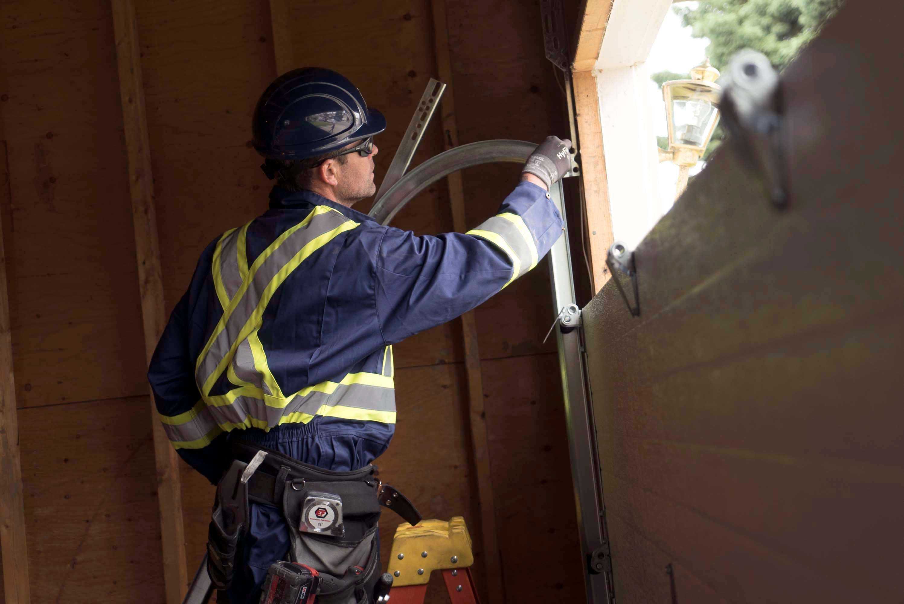 a cds technician performing track maintenance for a garage door