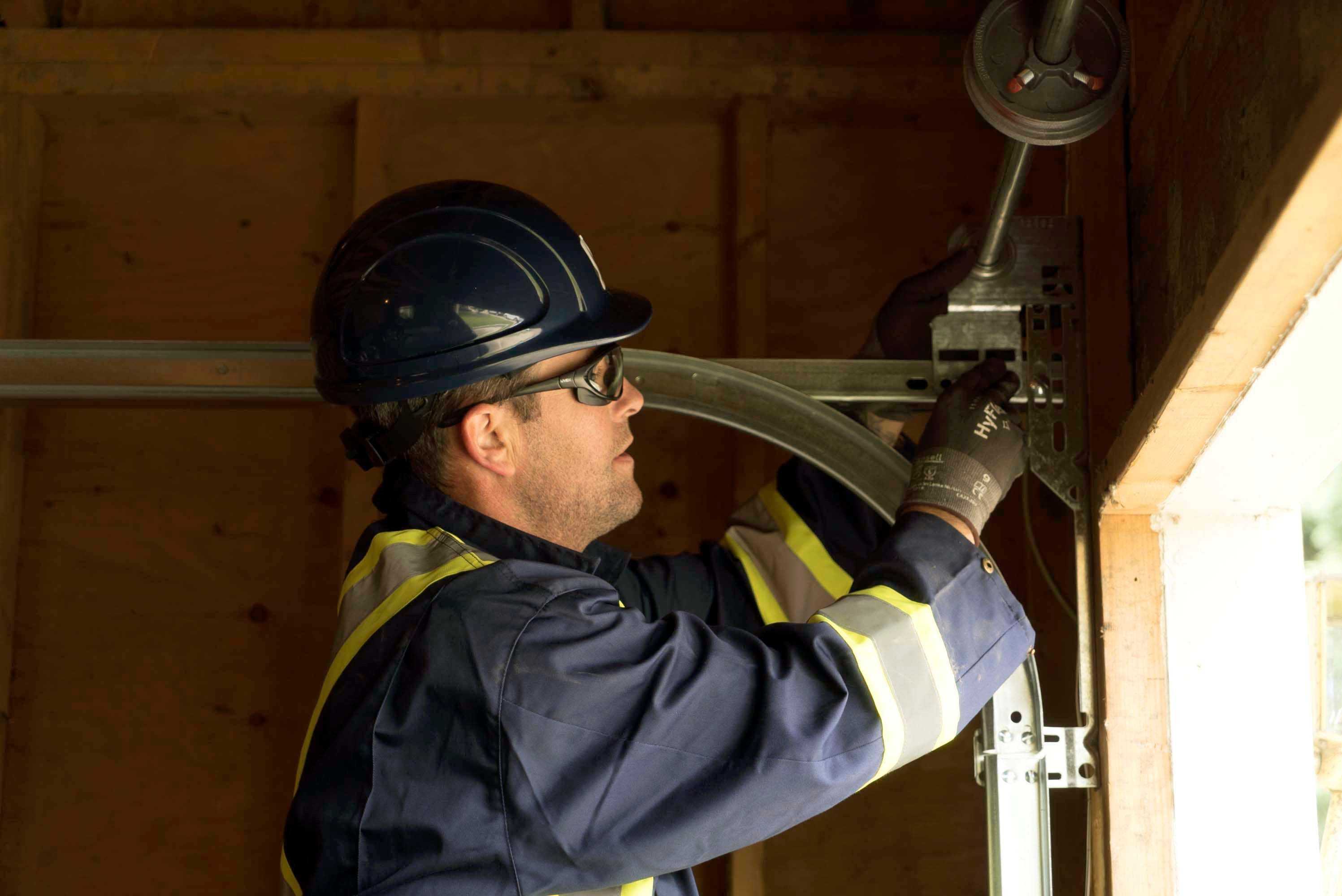 residential garage door repair technician inspecting tracks