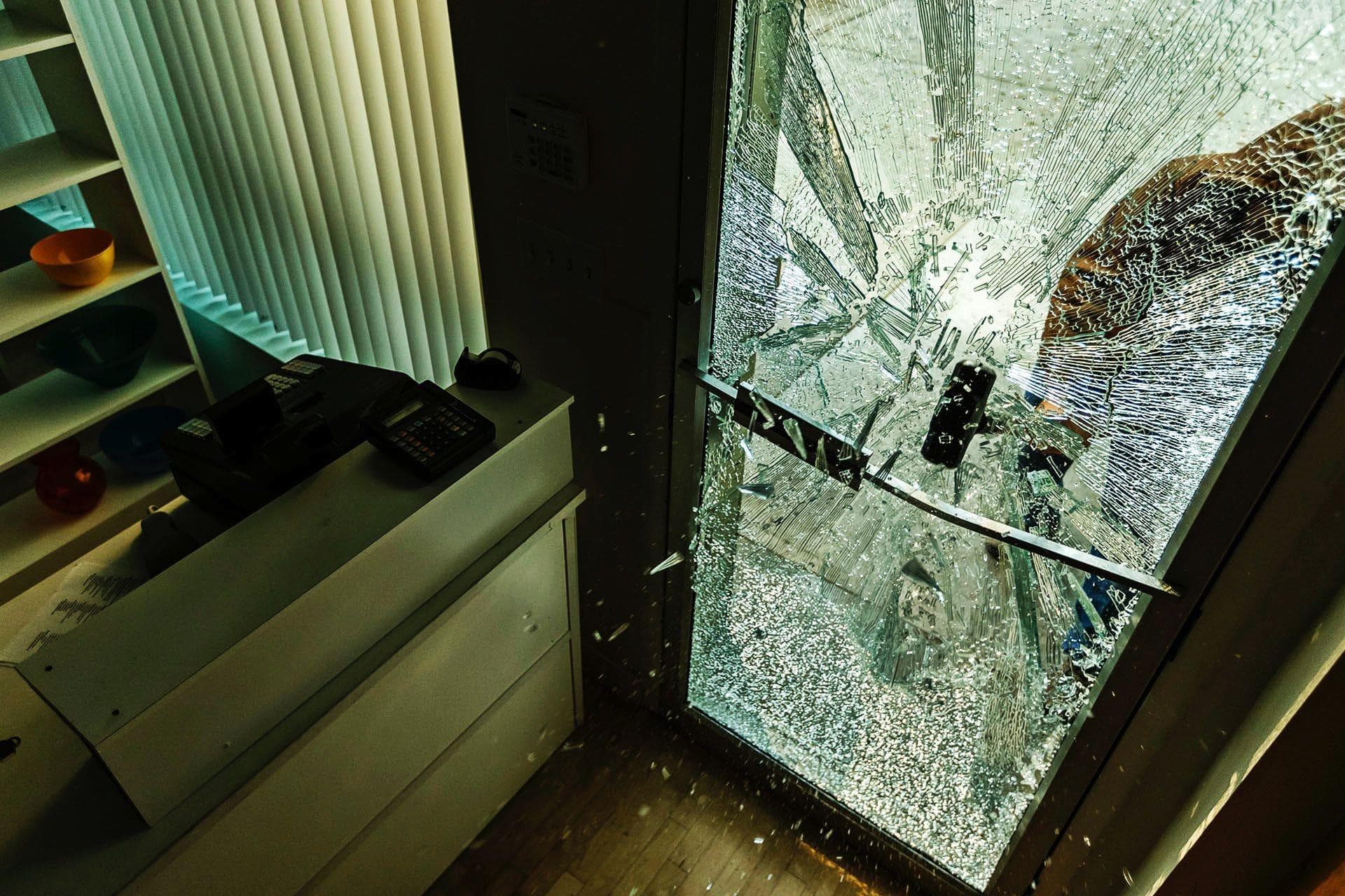 robber using a sledgehammer to break through commercial glass door