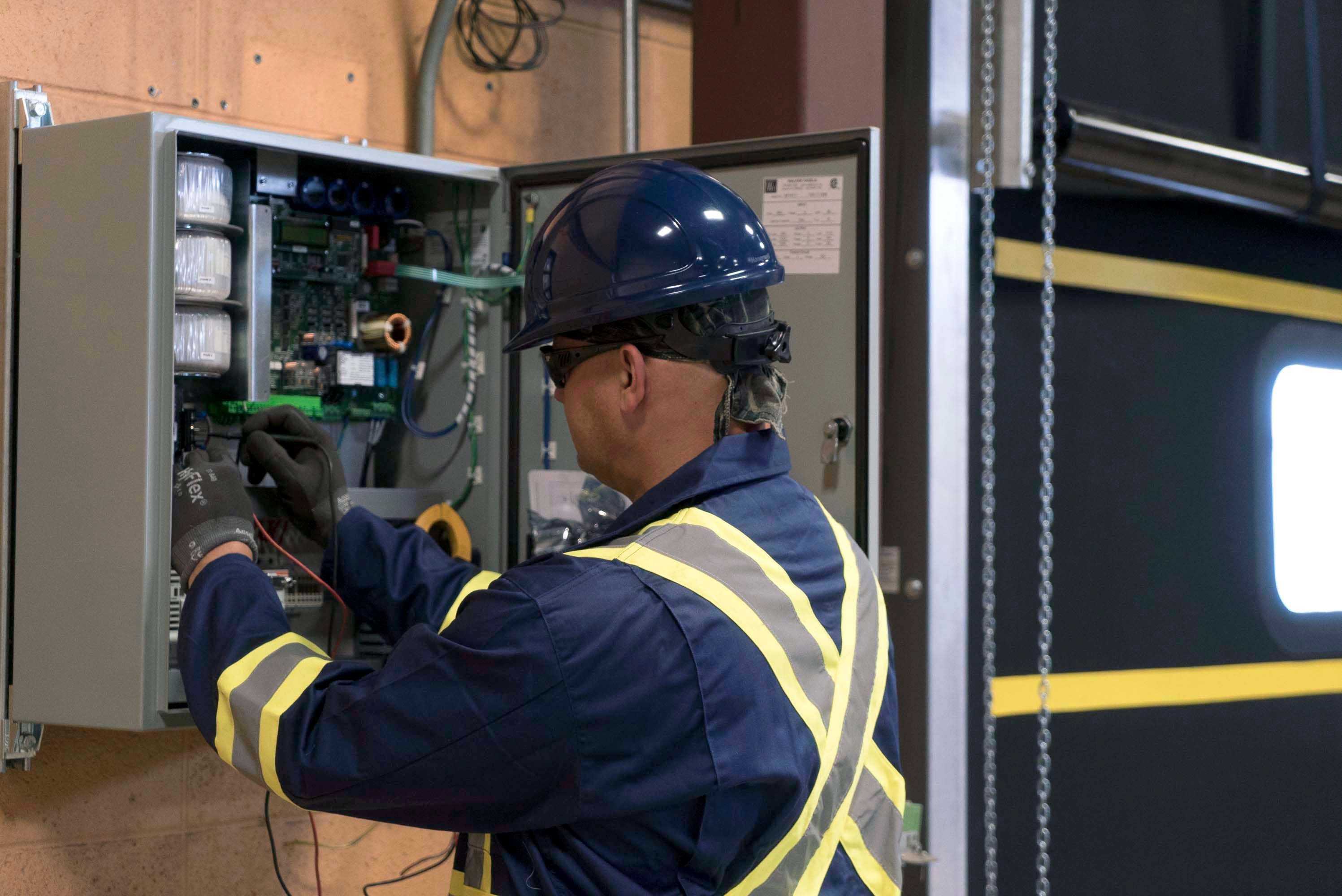 CREATIVE DOOR Commercial technician servicing sectional door in large warehouse CREATIVE DOOR Commercial technician servicing sectional door in large warehouse