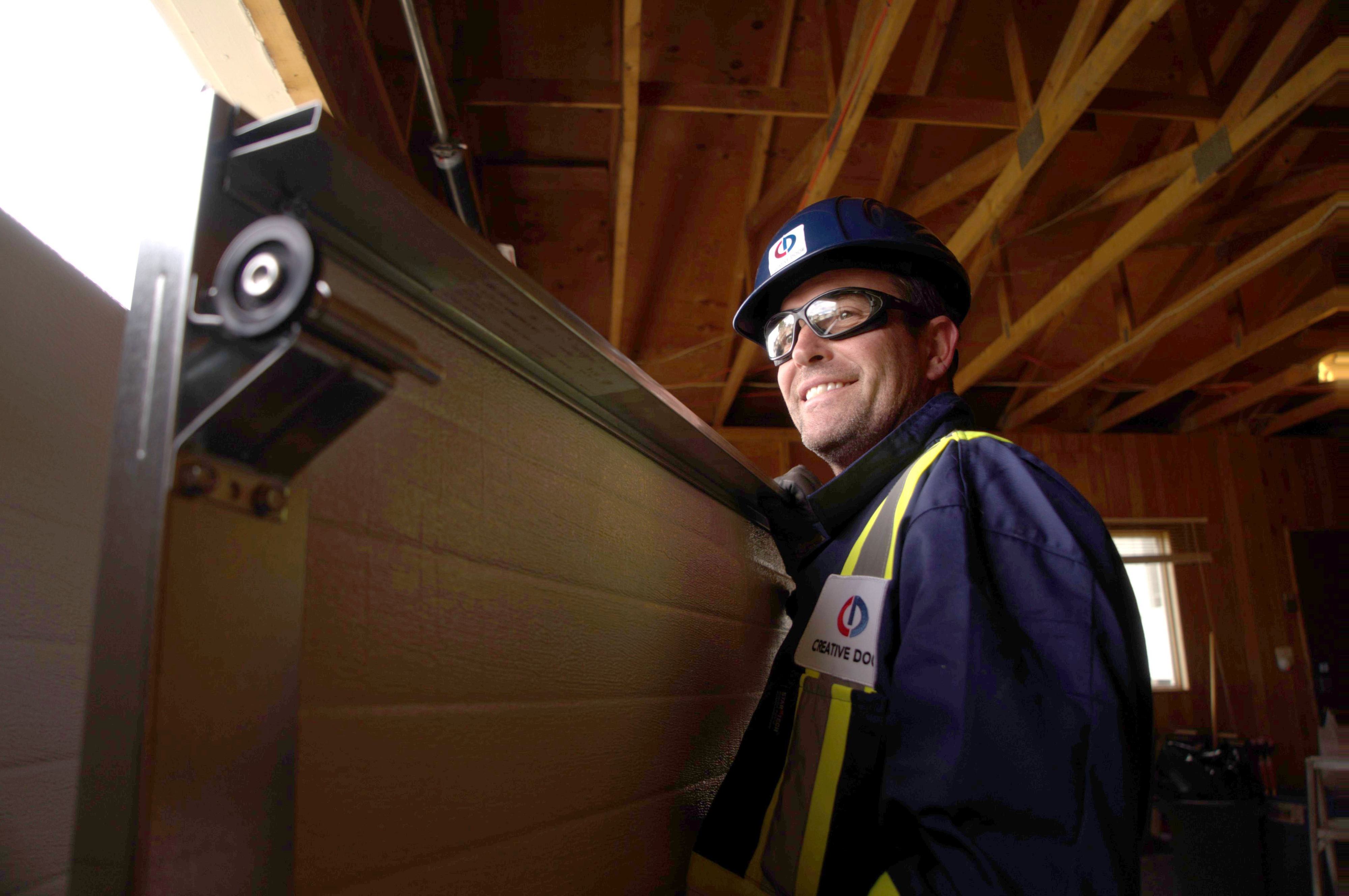 smiling garage door repair technician from creative door services inside a garage
