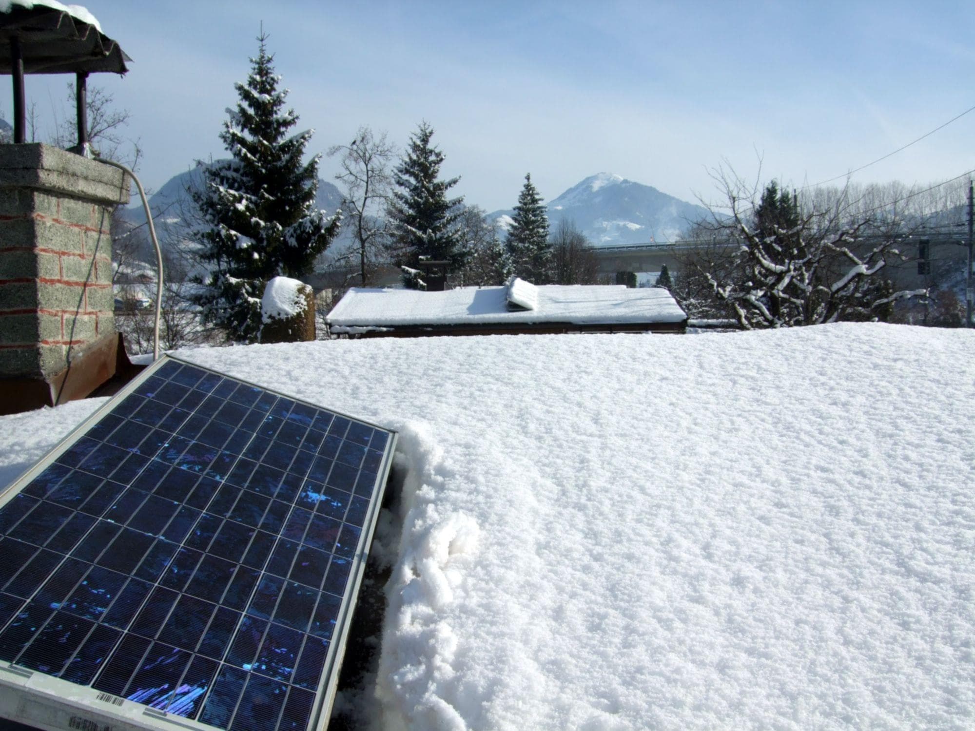solar panel on snowy residential roof with mountains in background