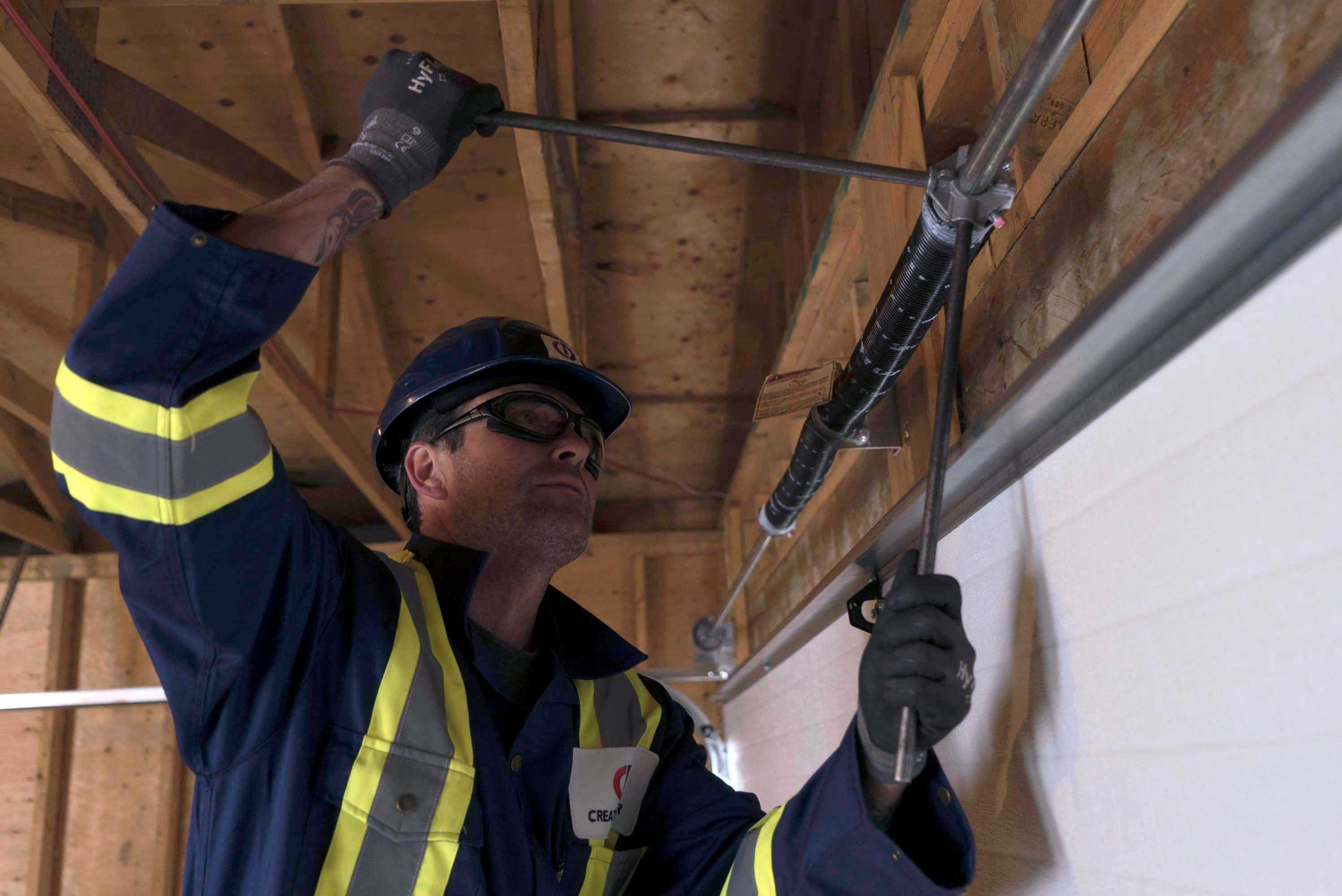 a creative door repair technician tightening garage door springs