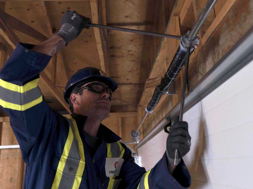 Creative Door Services technician repairing garage door spring