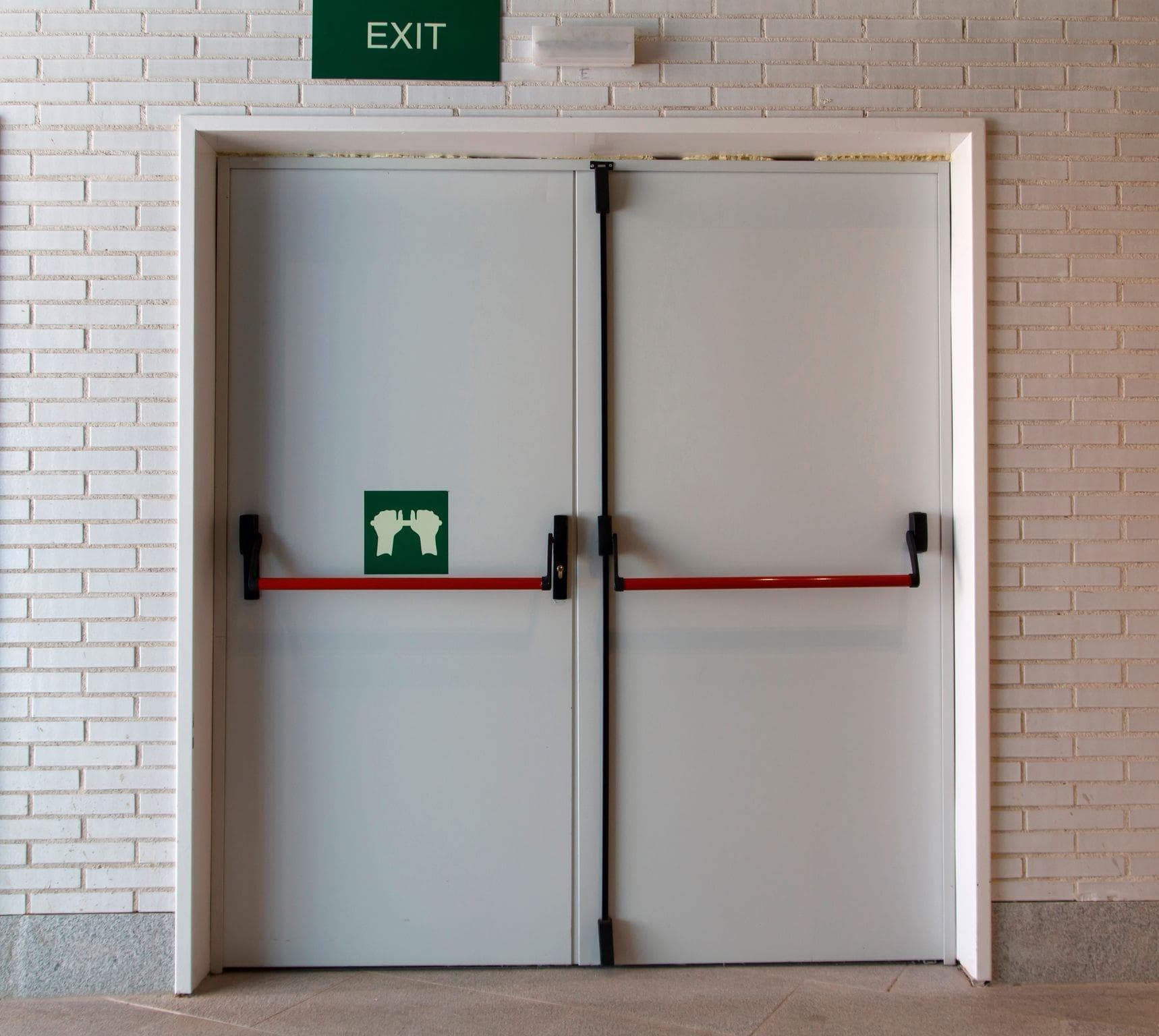 steel exit doors with white brick wall