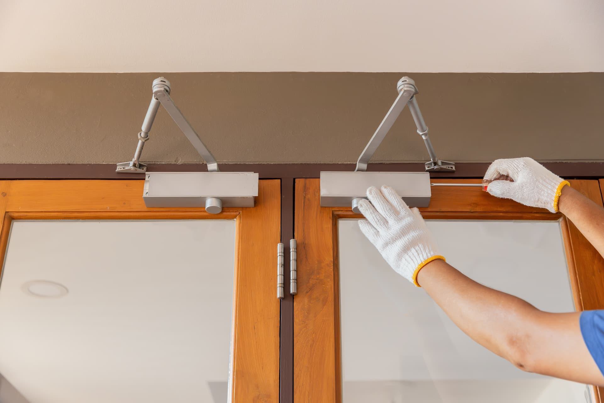technician adjusting pedestrian door closer and hydraulic arm