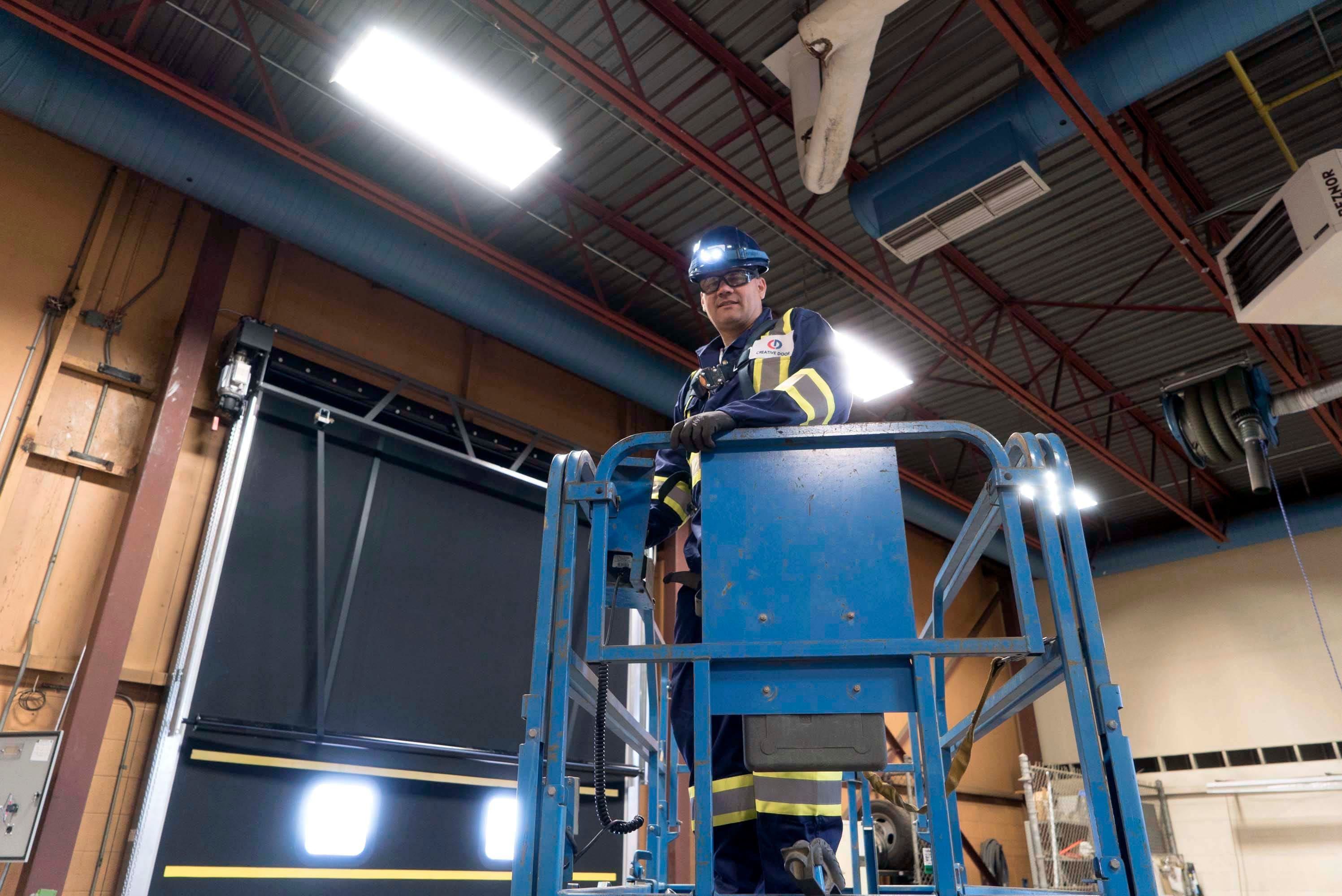 a professional technician in a lift truck to reach overhead commercial door springs