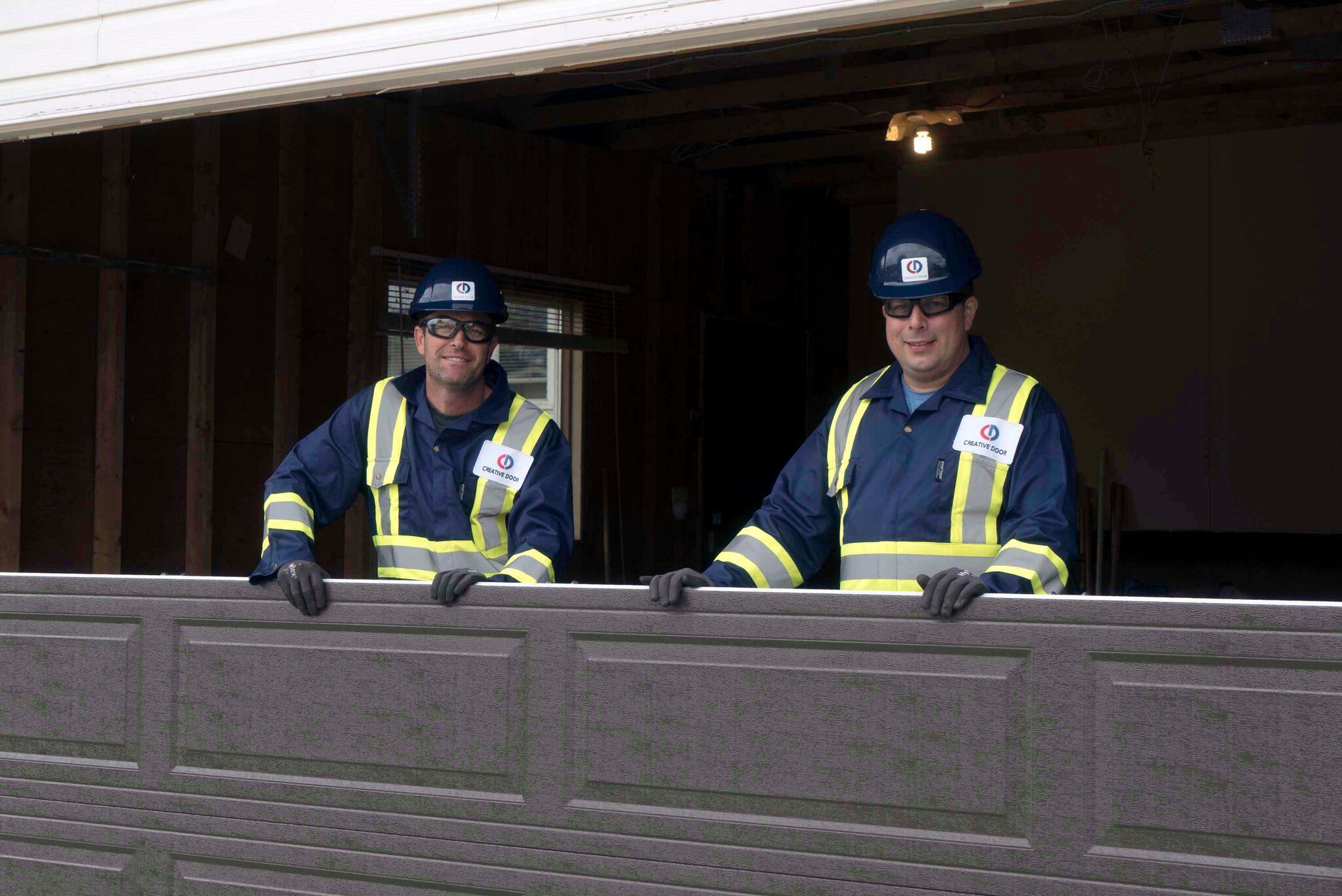Creative Door technicians holding new garage door panel section to install Creative Door technicians holding new garage door panel section to install