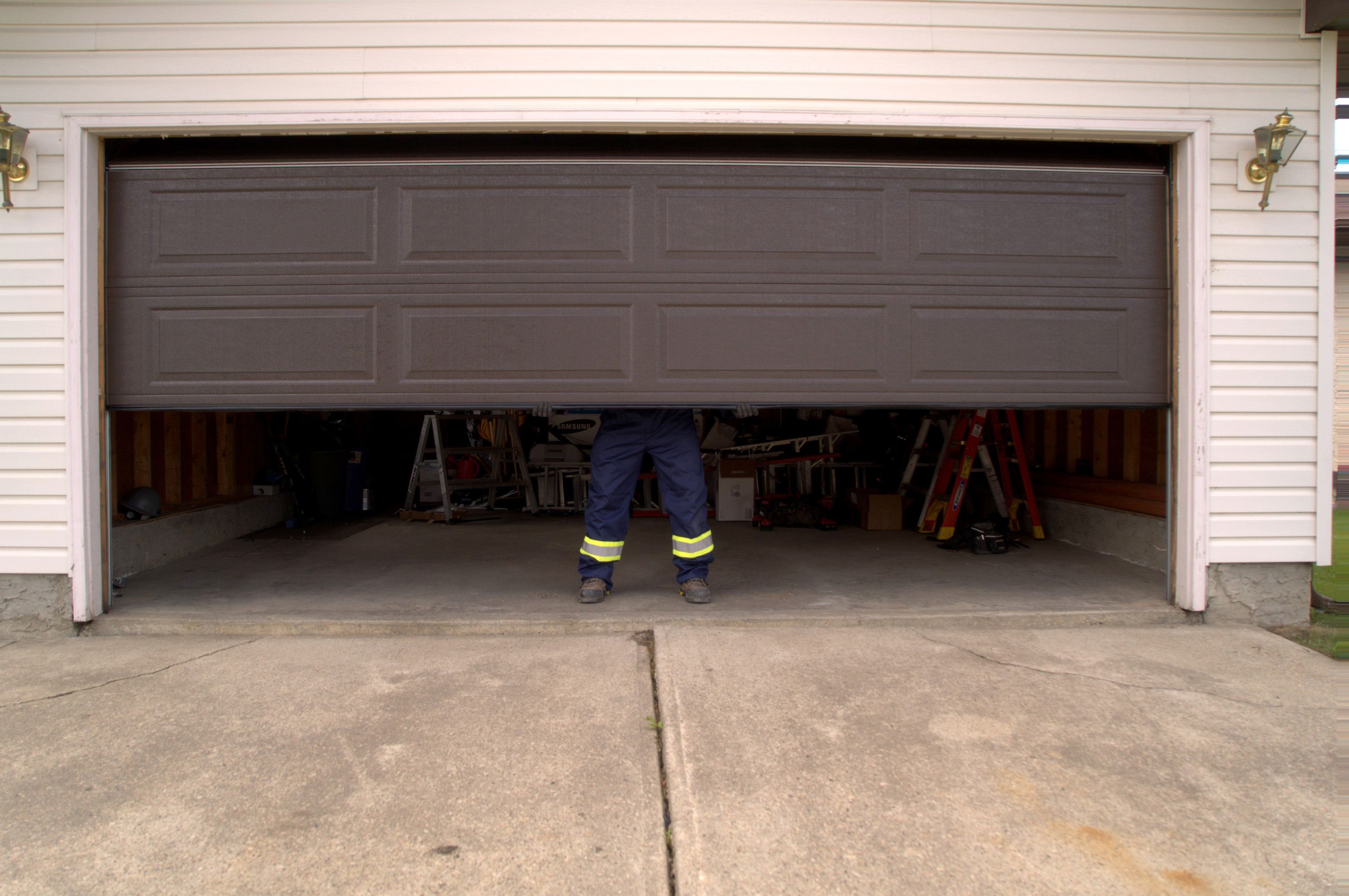 garage door stuck midway with technician in background troubleshooting