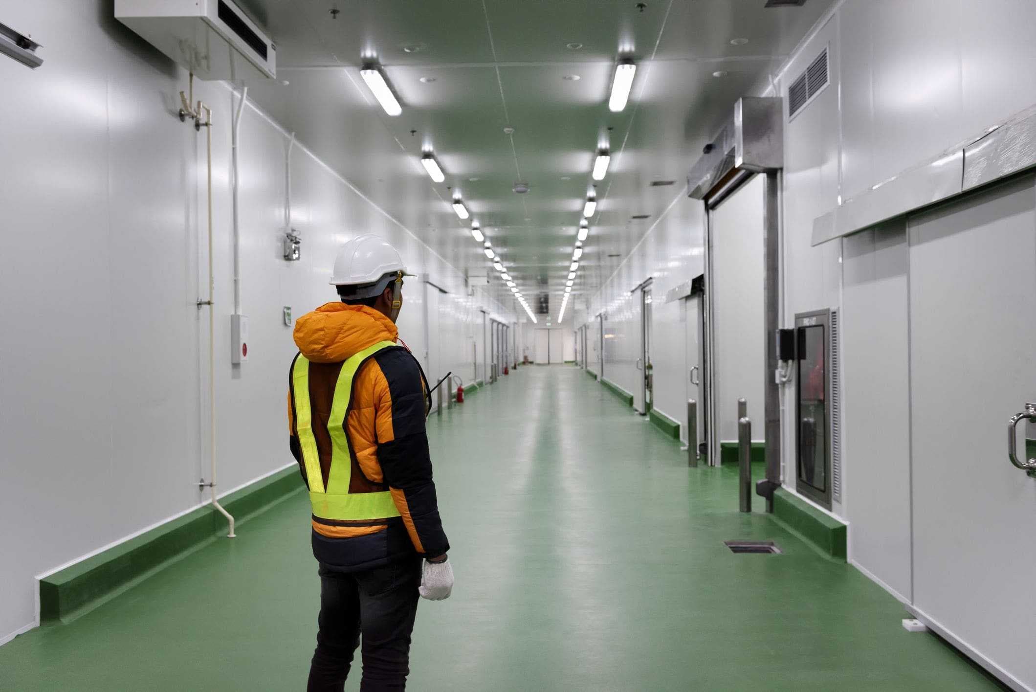 worker in safety vest standing in warehouse corridor 