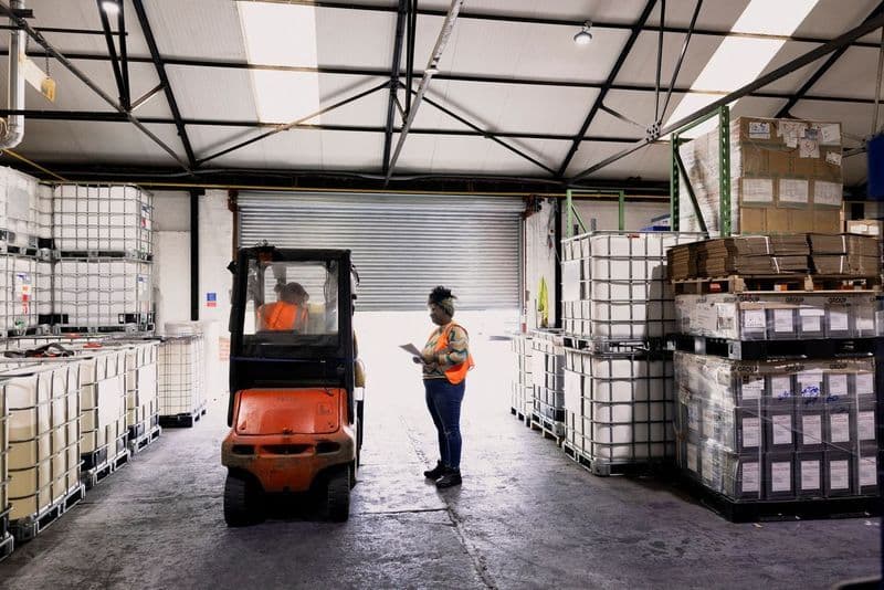warehouse loading dock with workers in orange vests
