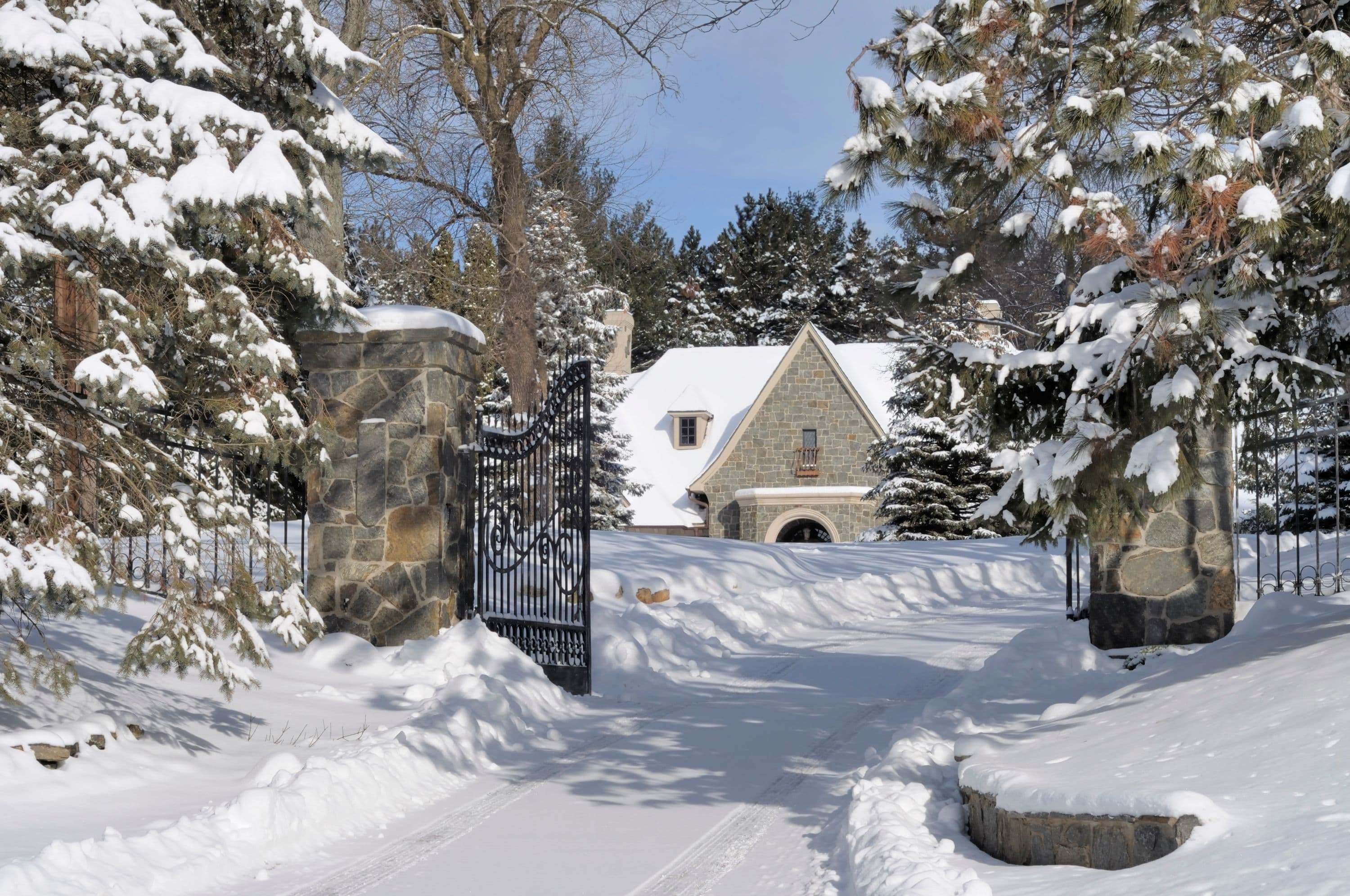 beautiful stone and steel gate with fresh snowfall around winter estate