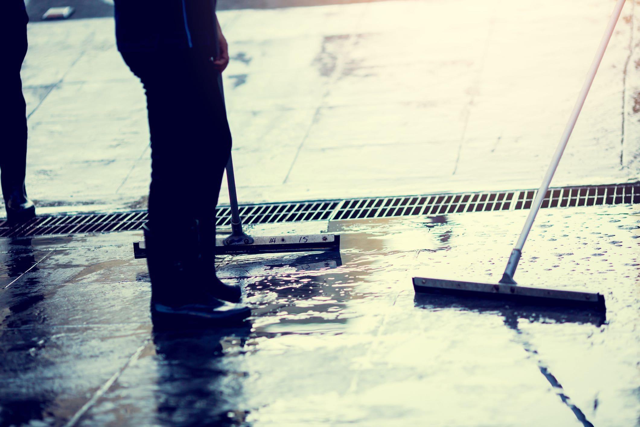 using a floor squeegee to sweep out water from garage using a floor squeegee to sweep out water from garage
