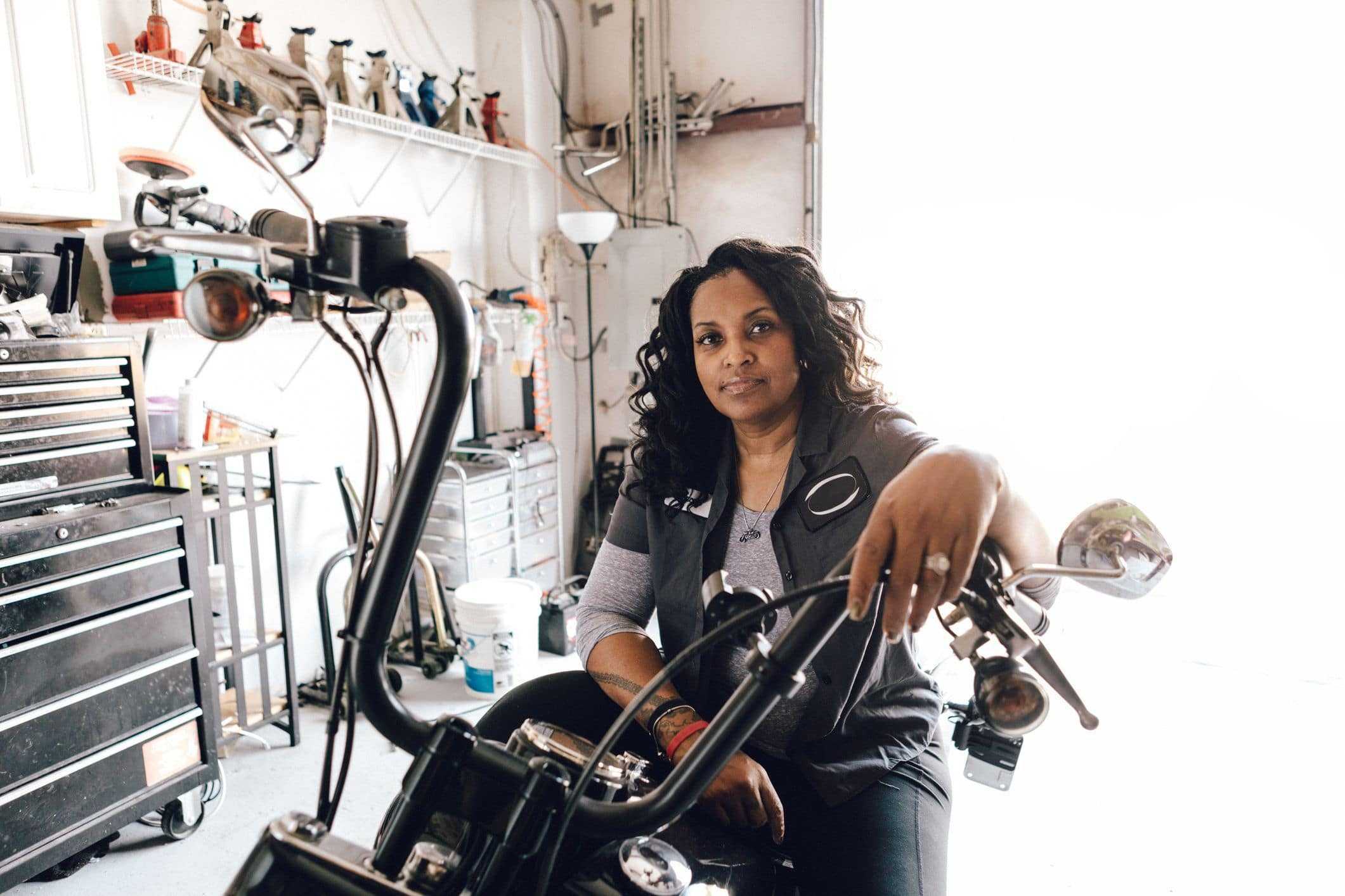 confident woman sitting on motorcycle in garage