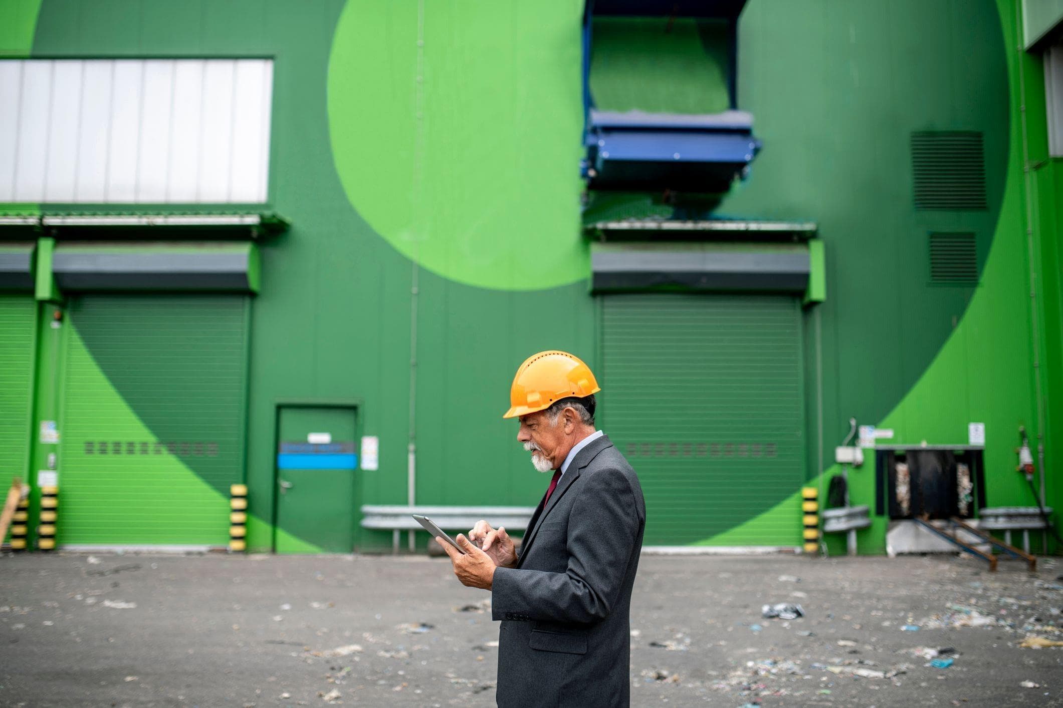 site manager outside colourful green warehouse with pedestrian doors
