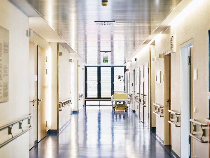 Hospital corridor with patient room doors and medical equipment in a healthcare facility