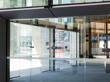 Modern glass pedestrian door at an office building entrance with automatic access system