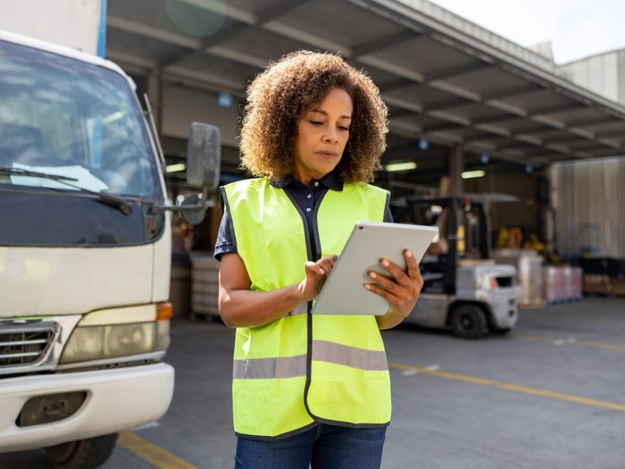 Woman supervising the dispatch of trucks at a distribution warehouse 1472189909 min