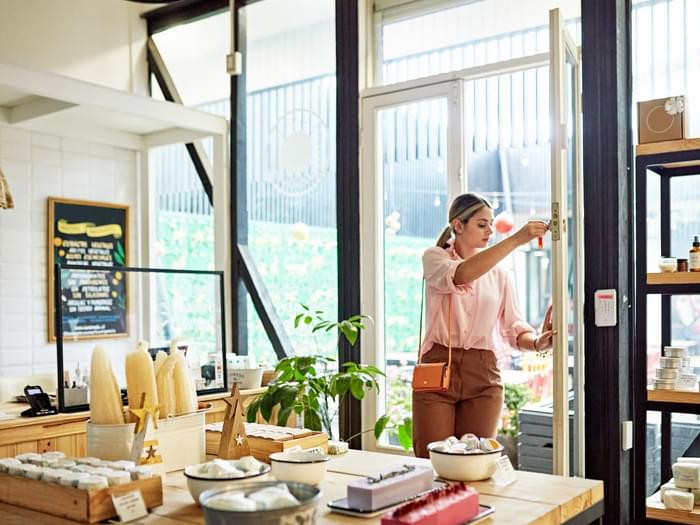 Young business owner unlocking front door of retail shop