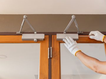Technician adjusting pedestrian door closer arm